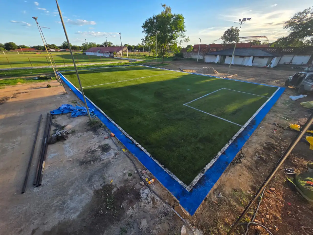 Cancha de fútbol con césped sintético recién instalado, demarcación blanca y perímetro de color
